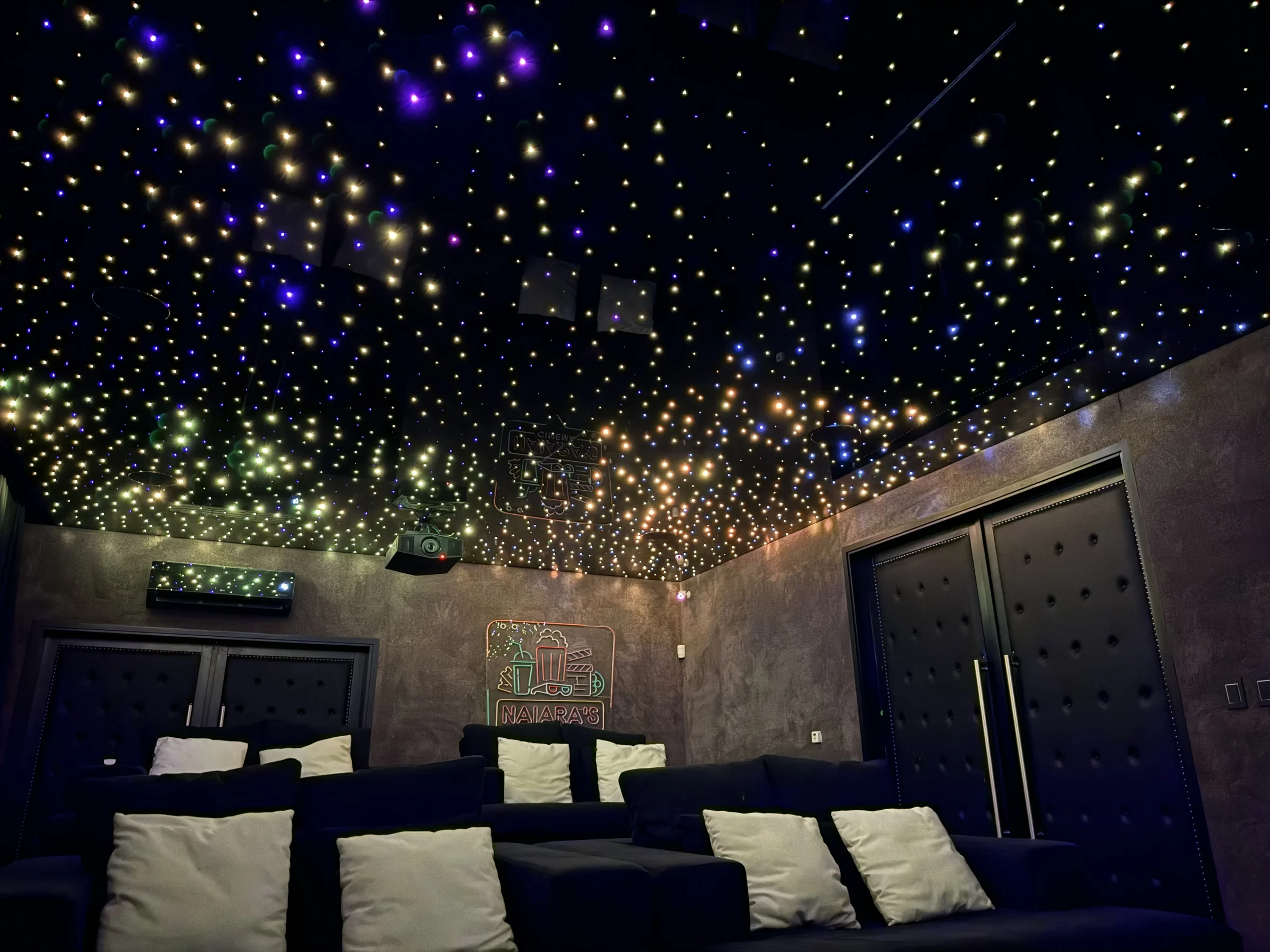 Sala con sofás y cielorraso estrellado con luz cálida realizado por Luminova